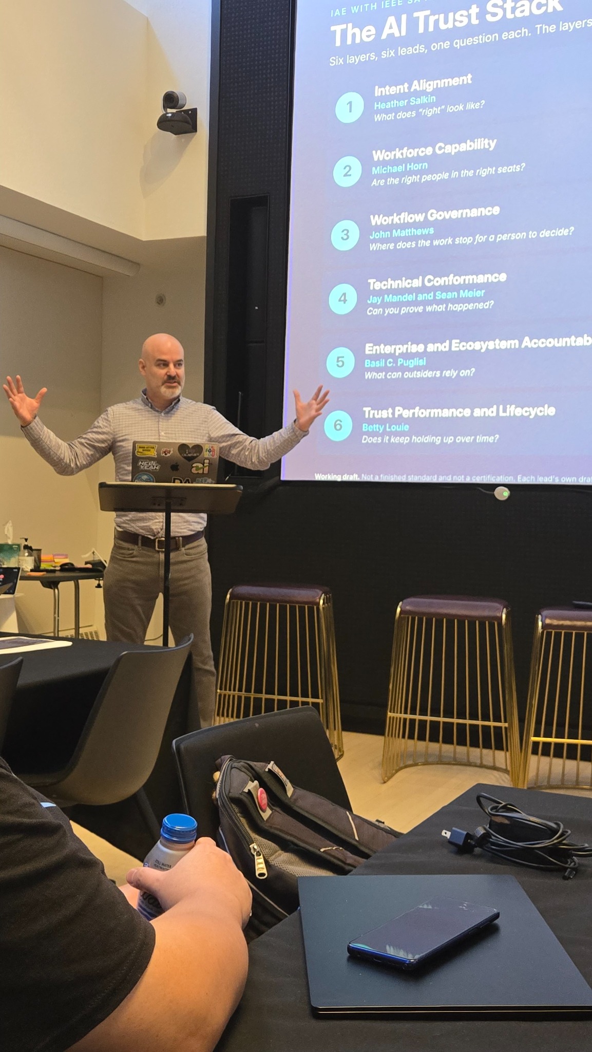 Jay Mandel speaking with his hands raised at the IAE summit