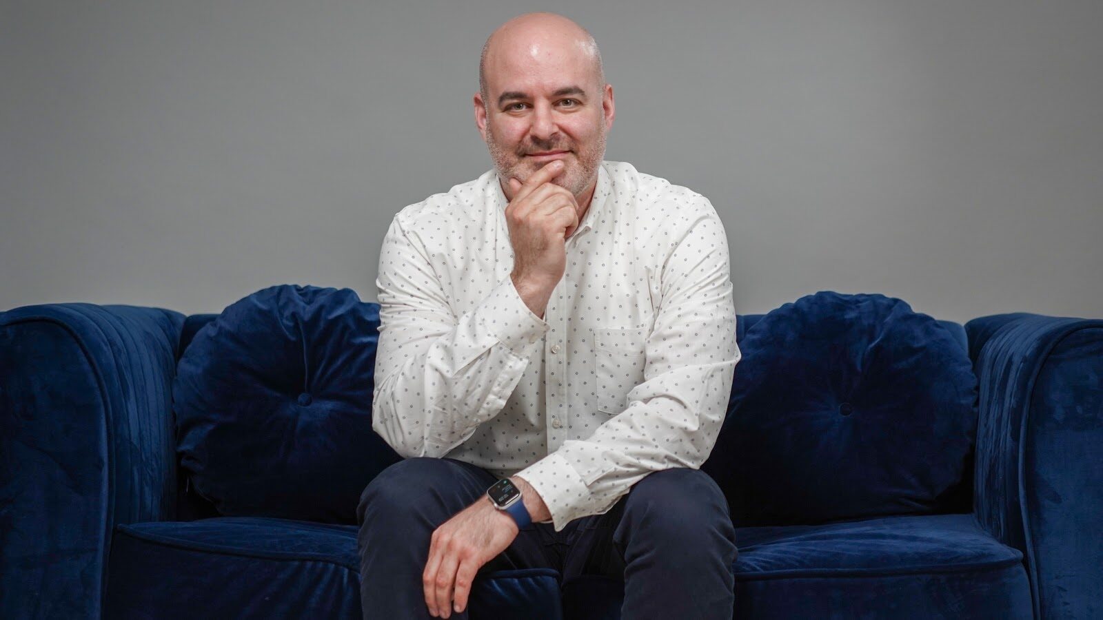 Jay Mandel seated on a blue sofa, listening