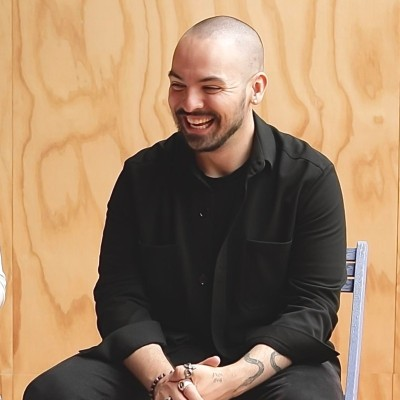 Sean Meier, smiling in a black shirt, seated in front of a light wood wall